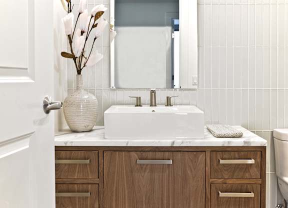 a bathroom with a white sink and a vase with flowers