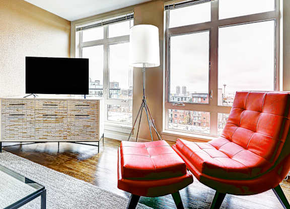 Living room with red leather chair and floor lamp at The Lyric Apartments, Seattle, WA 98102