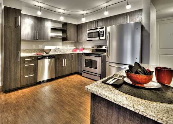 Kitchen with granite countertops and wood grain cabinetry at The Lyric Apartments, Seattle, WA