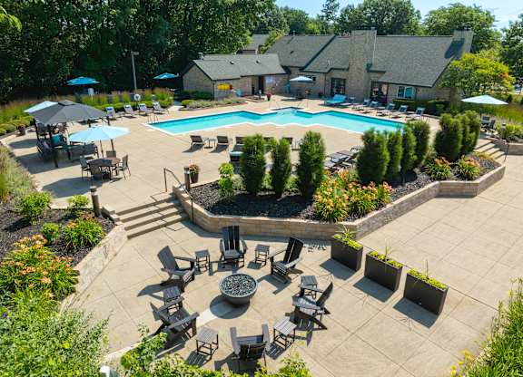 A large outdoor swimming pool surrounded by a patio with chairs and umbrellas.