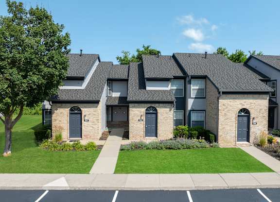 A row of houses with a green lawn in front.