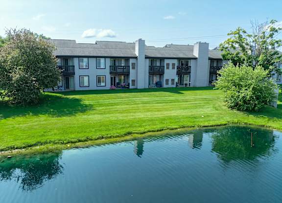 A large white building with a pond in front.
