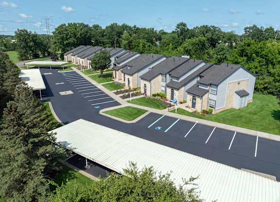 A parking lot in front of a building with a green lawn.