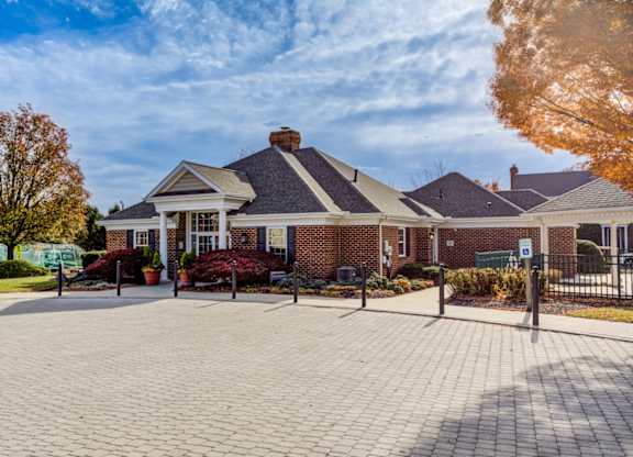 A brick building with a black roof and a sign on a post at Highlands at Warwick Apartments, Lilitz, Pennsylvania