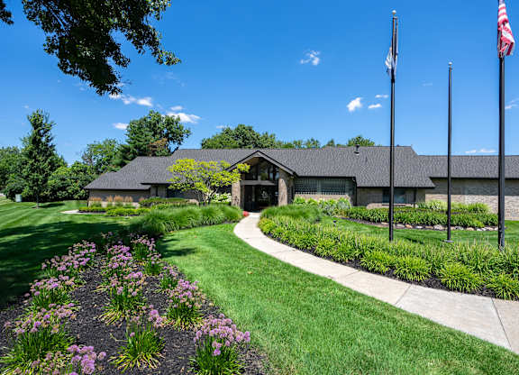 A building with a flag on top and a garden in front.