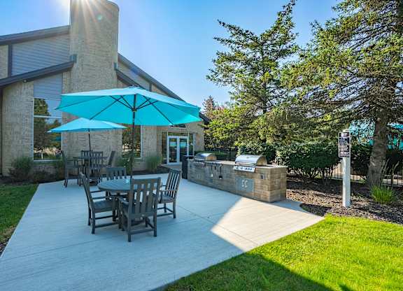 A patio with a table and chairs under a blue umbrella.