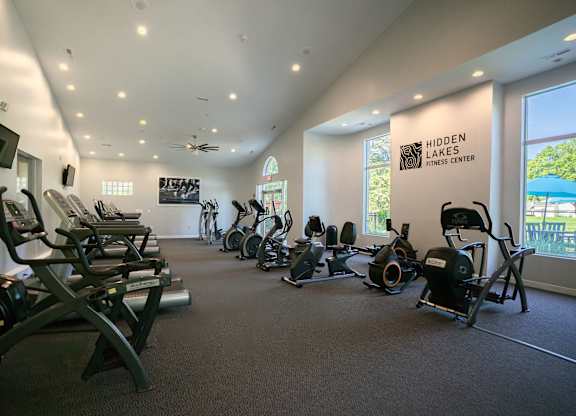 A gym with a row of exercise bikes and a sign that says Hidden Lakes Fitness Center.