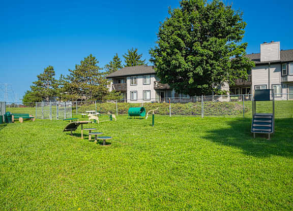 A green grassy area with a picnic table and a green barrel.