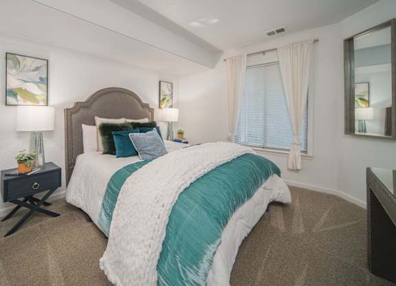 A bedroom with a large bed and a mirror on the wall.