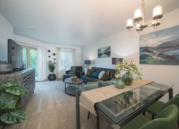 A living room with a glass table and green chairs.
