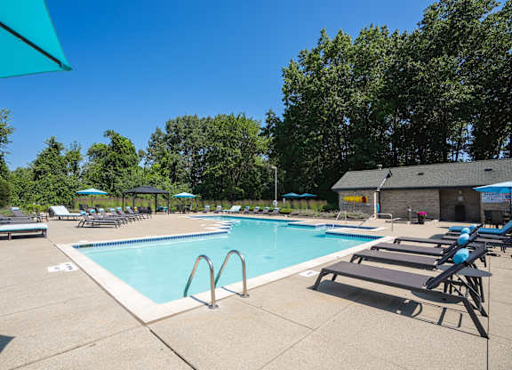 A large outdoor swimming pool surrounded by sun loungers and umbrellas.