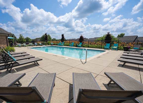 A pool surrounded by wooden benches on a sunny day.