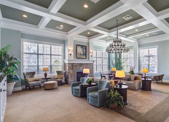 A large, well-lit living room with a variety of seating options and a chandelier at Meridian West Shore, Pennsylvania 17055