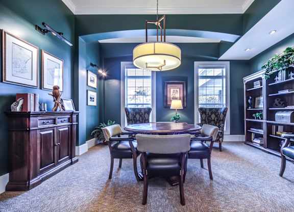 A room with a table and chairs in the center with a bookcase to the right at Meridian West Shore, Mechanicsburg Pennsylvania