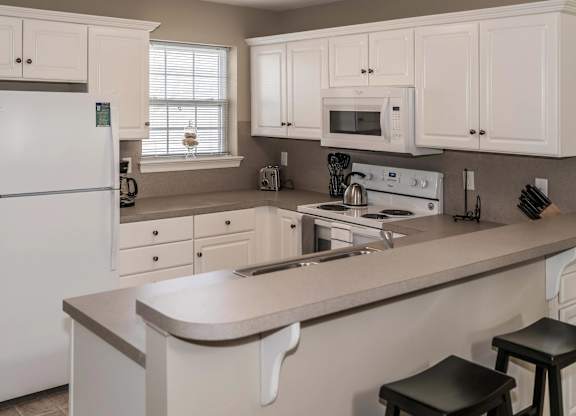A white kitchen with a refrigerator, microwave, oven, and sink at Highlands at Warwick Apartments, Lilitz, PA 17543