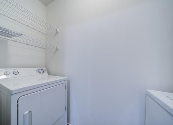A white dryer is in a small room with a white wall at The Crest at Elm Tree, Mount Joy, PA