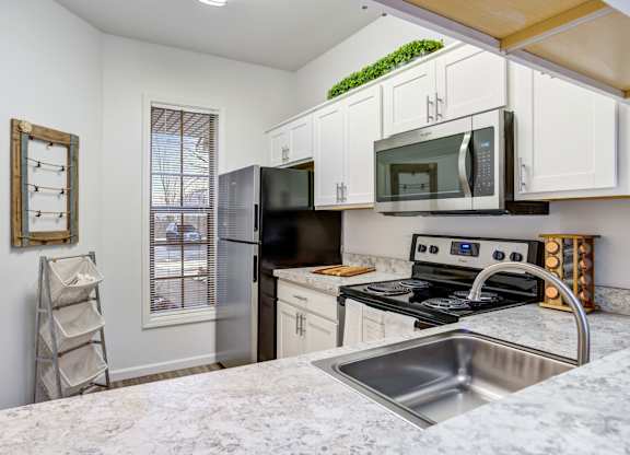 Kitchen with stainless steel sink and white cabinets at Woodland Meadows, Clinton Township, MI, 48035