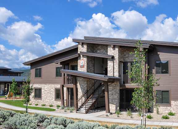 A modern house with a stone facade and a large front yard.
