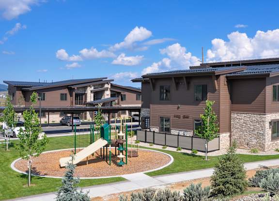 A playground with a slide is in front of a building.