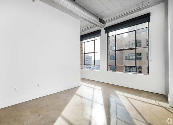 A large empty room with a window overlooking a cityscape.