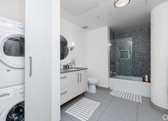 A modern bathroom with a washing machine built into the cabinetry.