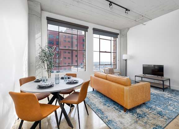 A living room with a white table and orange chairs.