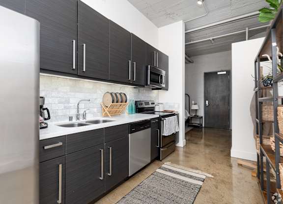 A kitchen with black cabinets and a white fridge.