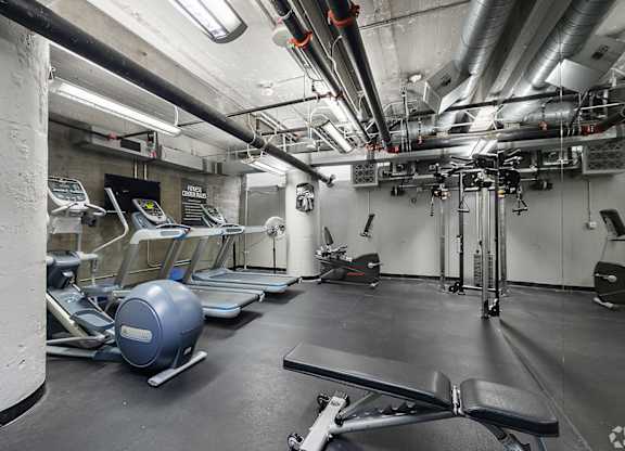 A gym with a variety of equipment including treadmills, exercise balls, and weight machines.