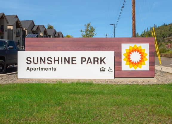 a sign for sunshine park apartments with a sunflower on it
