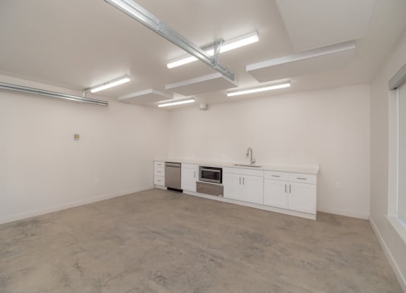 the interior of an empty room with white cabinets and a counter top and a sink
