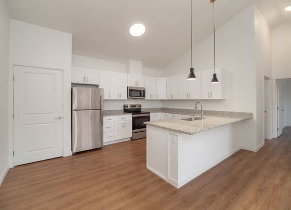 an empty kitchen with white cabinets and a counter top