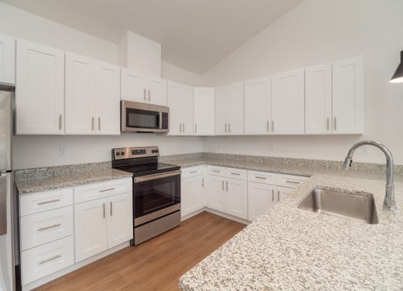 a kitchen with granite counter tops and white cabinets