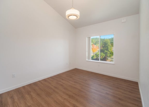 an empty living room with wood floors and a window