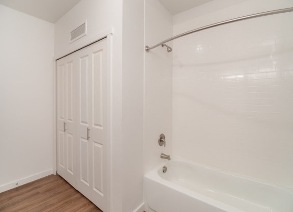 a bathroom with a white tub and shower and a white door