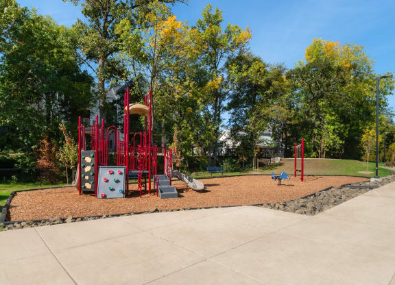 a playground with a red playset in a park