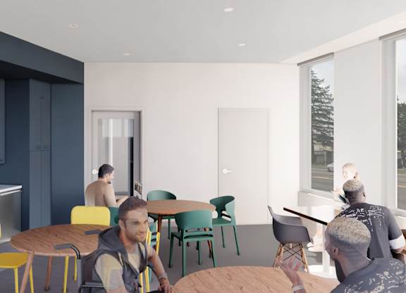 A group of people are sitting around a table in a room with a window overlooking a street.
