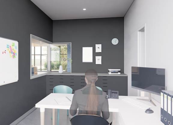 A person is sitting at a desk in a room with a whiteboard, a window, and a computer.