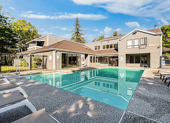 A large swimming pool in front of a building with a sunny day.