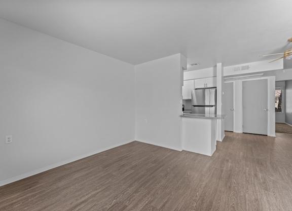 A spacious room with wooden flooring and white walls.