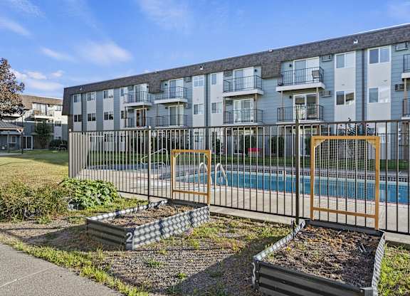 an apartment building with a pool behind a fence