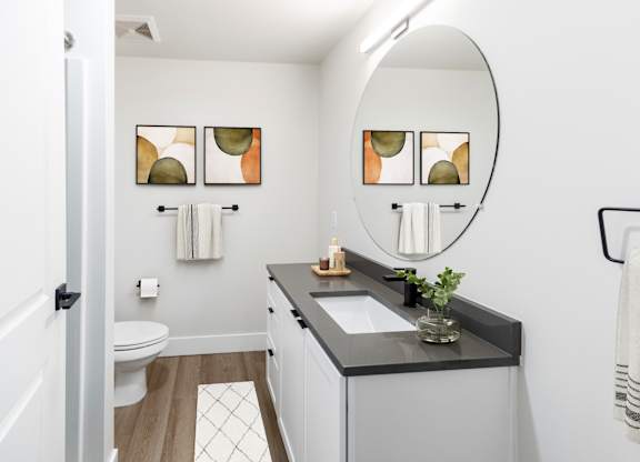A bathroom with a white toilet, a sink, and a mirror.