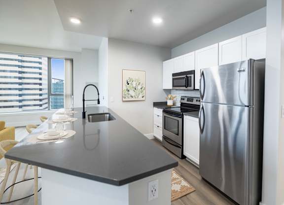 A modern kitchen with a black countertop and stainless steel appliances.