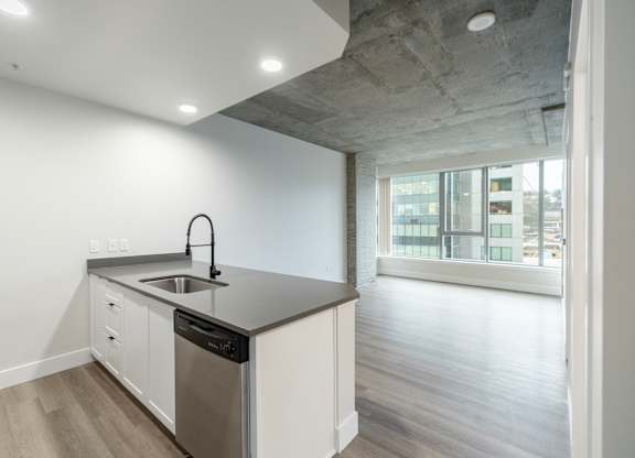 A modern kitchen with a concrete ceiling and a large window.