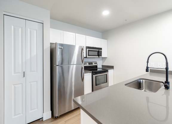 A modern kitchen with a stainless steel refrigerator, oven, and microwave.