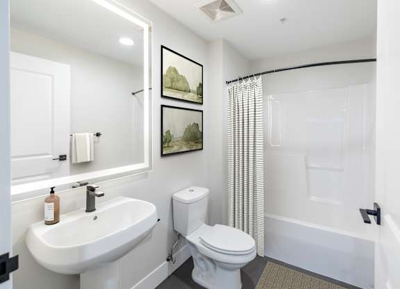 A white bathroom with a toilet, sink, and shower.