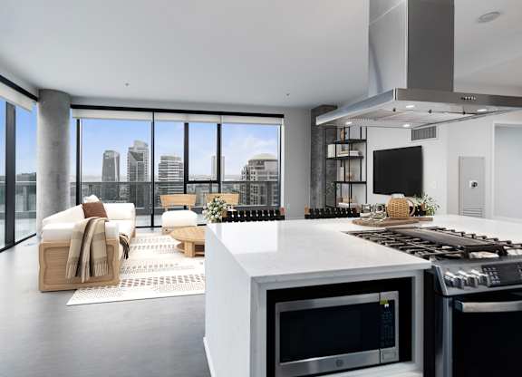 A modern kitchen with a view of the cityscape outside the large windows.
