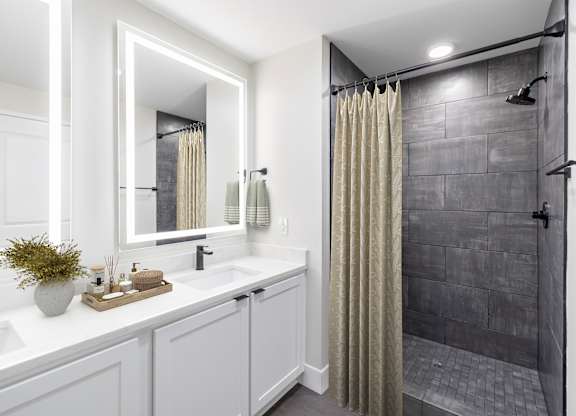 A bathroom with a white sink and a grey shower.