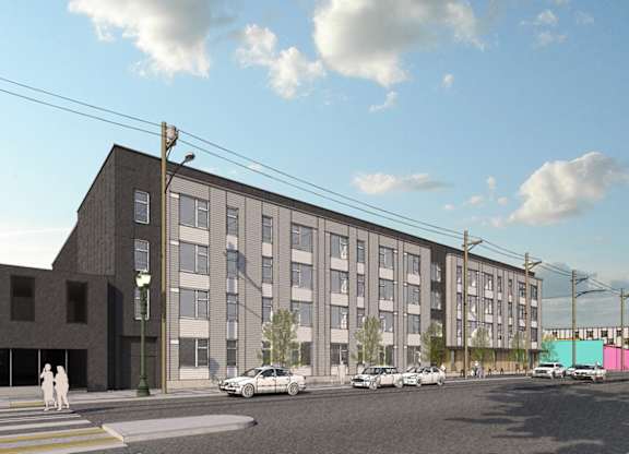 A street view of a modern building with cars parked in front.