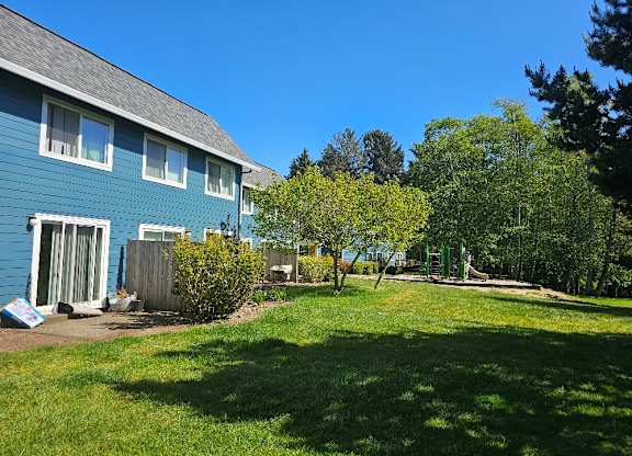 A blue house with a green lawn in front.