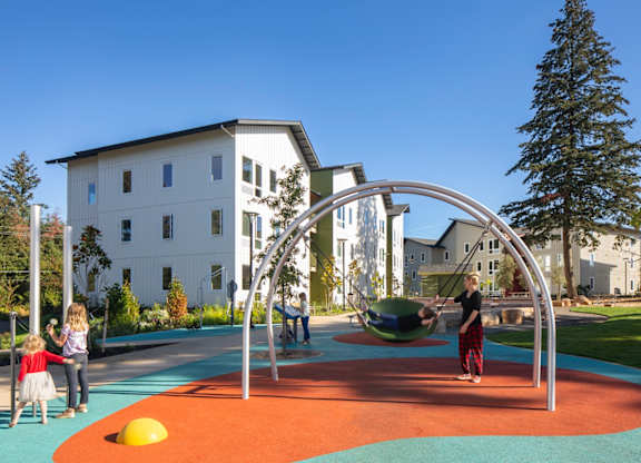 A playground with a swing set and children playing.